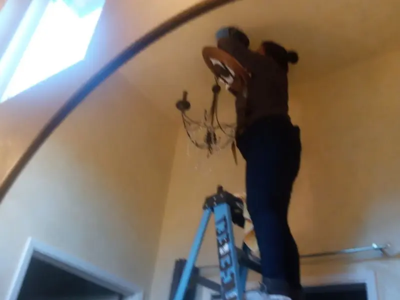 Electrician installing a chandelier in a Haines City residence